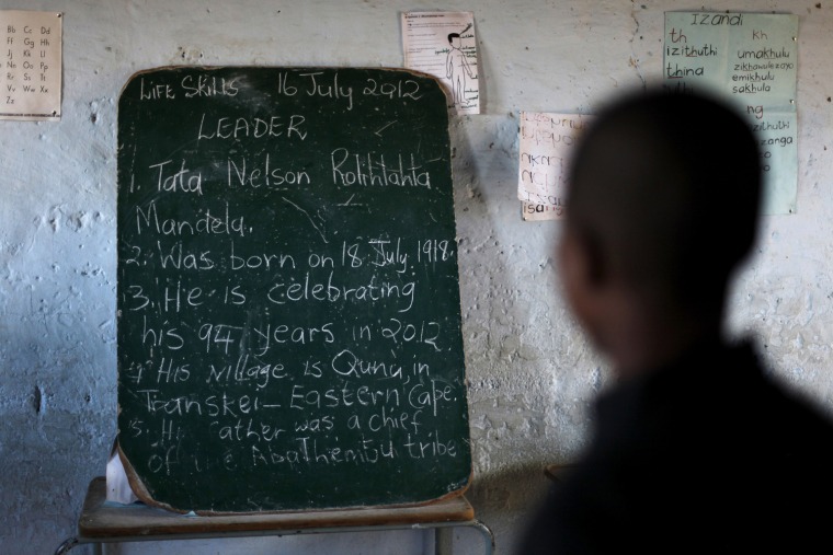 Image: School children read the history of former South African President Nelson Mandela written on a chalkboard, ahead of the opening of a container library by the Bill Clinton foundation in celebration of Mandela day, at a school in Qunu